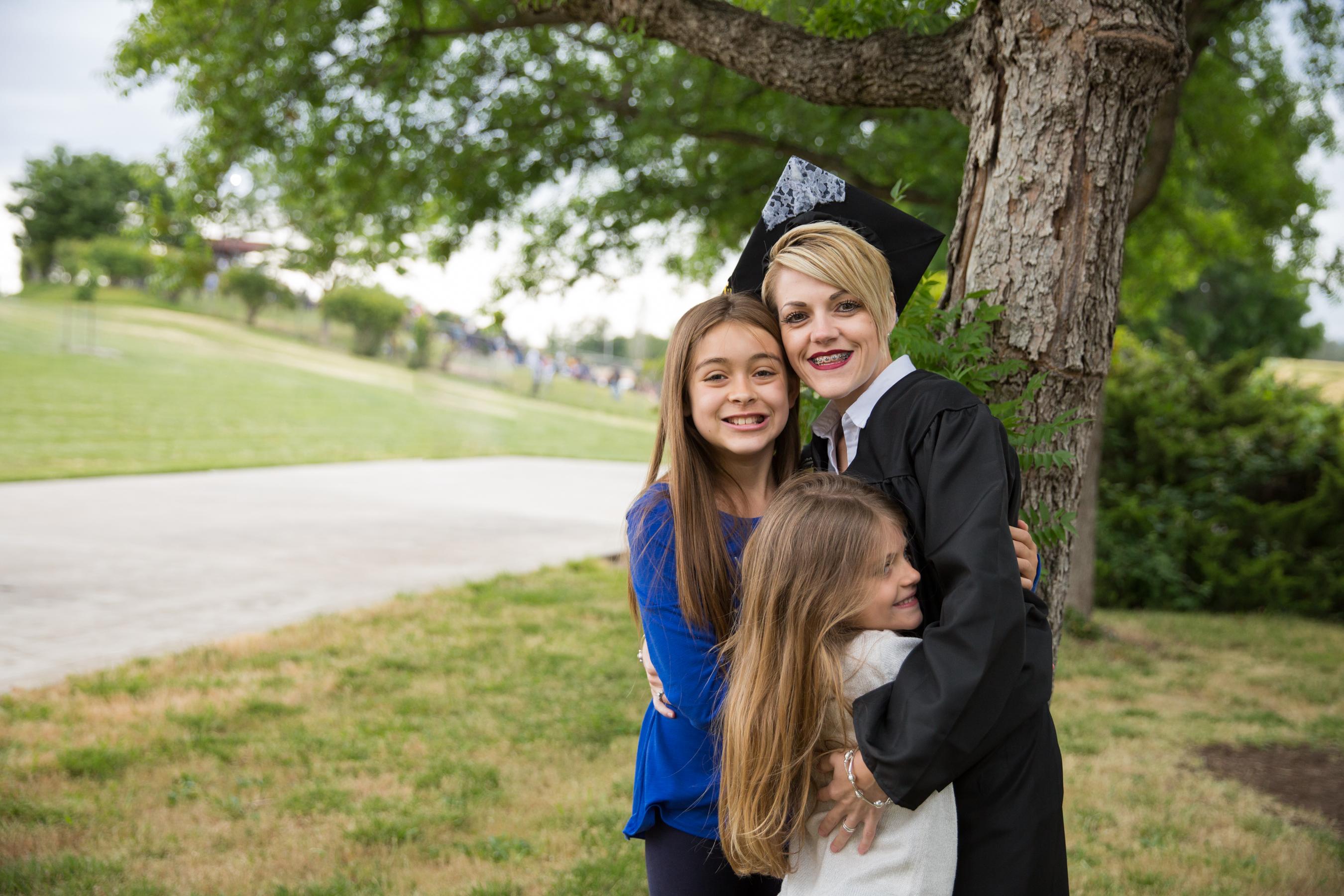 戴帽穿长袍的女学生抱着两个女儿